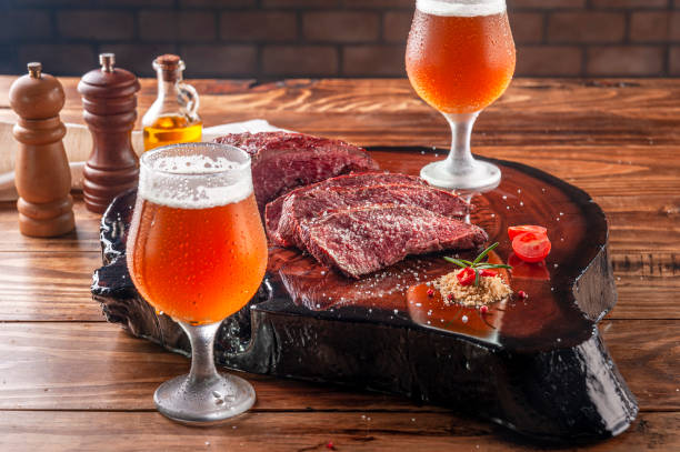Grilled denver steak with beer Grilled denver steak on wooden cutting board with two sweaty cold tulipa glasses of ale draft beer. Marble meat beef. blade roast stock pictures, royalty-free photos & images
