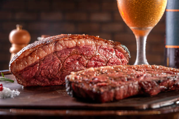 Grilled cap rump steak and beer (brazilian picanha) Grilled sliced cap rump steak with two glasses of beer on wooden cutting board. Marble meat beef (Brazilian picanha). blade roast stock pictures, royalty-free photos & images