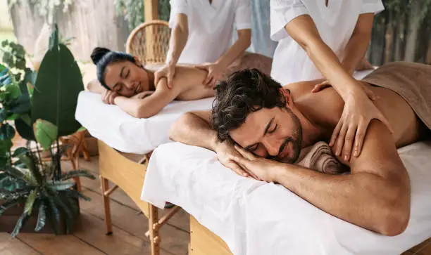 Photo of Couple massage at spa resort. Beautiful couple getting a back massage outdoor, romantic weekend and relax