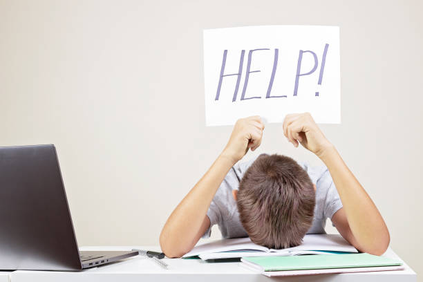 istock Learning difficulties, school, education, online remote learning concept. Sad frustrated tired exhausted kid with laptop computer holding card with Help word 1336350272