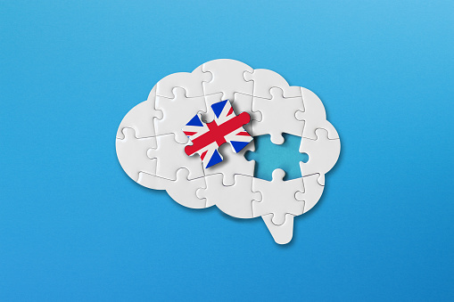 Concepto de aprendizaje de inglés, piezas de rompecabezas blanco con bandera británica una forma de cerebro humano sobre fondo azul photo