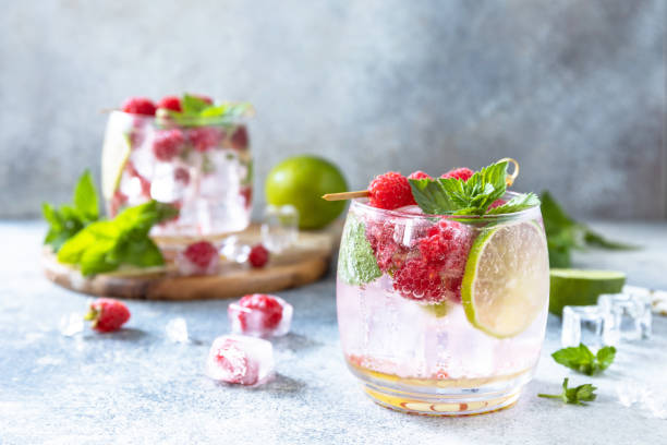 cóctel seltzer duro con frambuesas y lima sobre una mesa de piedra gris. espacio de copia. - raspberry soda fotografías e imágenes de stock