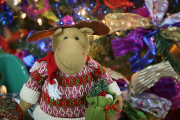 istock Stuffed reindeer sitting in front of Christmas tree 1336357096