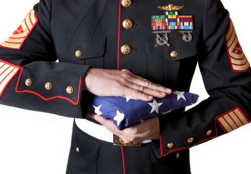 A Marine in dress blues holds a folded flag