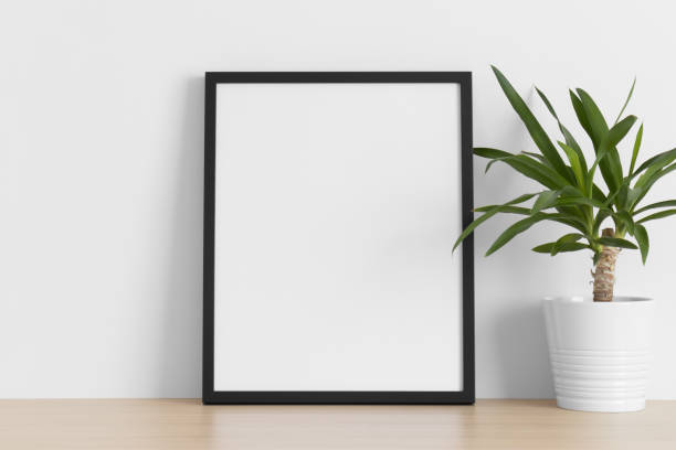 istock Black frame mockup with a yucca plant on the wooden table. 1336358448