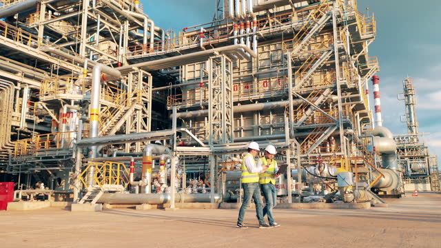 Two workers are walking through the premises of the oil refinery