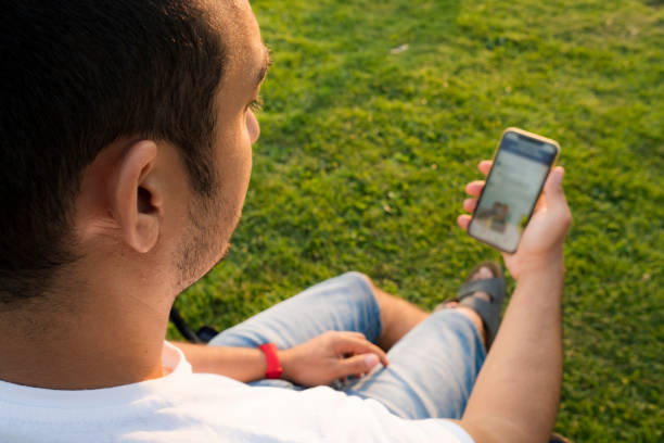 istock Young man sitting on grass and using smart phone. 1336359971