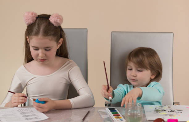 istock Two sisters of different ages paint with paints and make decorations for home holiday 1336360008