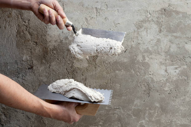 construction notched trowel and worker hands construction notched trowel and worker hands with white mortar on wall hand with a plaster spatula stock pictures, royalty-free photos & images