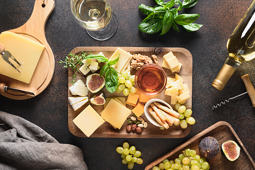 Cheese platter with grapes, nuts, figs on a brown background. Top view. Festive gourmet appetizer for holiday.