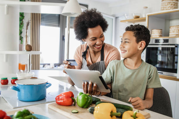 若い男の子と彼の母親は、オンライン食料品を注文しています - mother son family cooking ストックフォトと画像