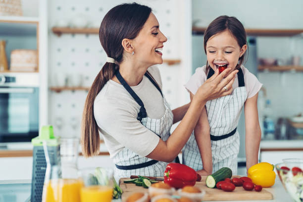 istock Mother giving tomato slice to her daughter 1336364012