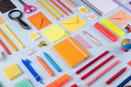 Back to school concept with crayons and school supplies on blue background