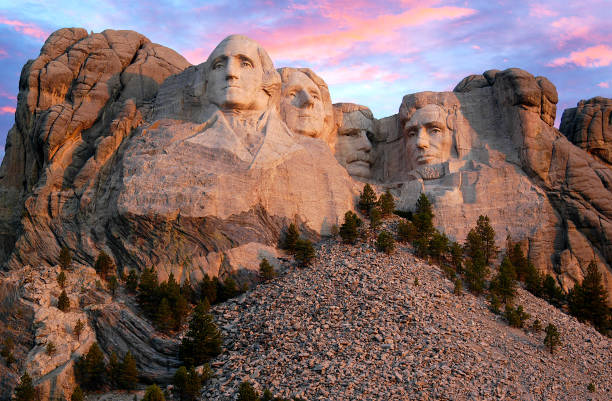 Mount Rushmore morning as the sun begins to light up the mountain range. As the sun peaks up over the horizon of Mount Rushmore, it begins to light up this South Dakota national landmark. theodore roosevelt us president stock pictures, royalty-free photos & images