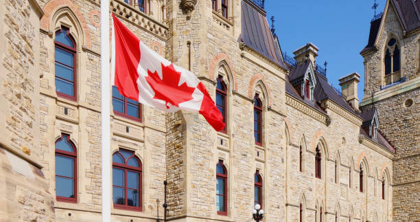 bandera canadiense a media asta frente al edificio del parlamento canadiense - canadian culture fotografías e imágenes de stock