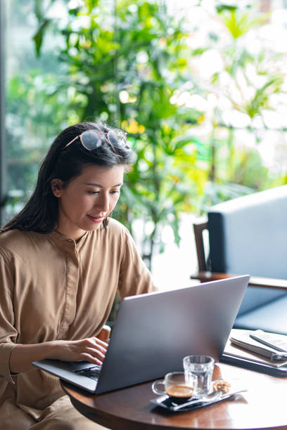 istock Asian Woman/College Student Using a Laptop Computer to Study Remotely at a Cafe 1336373167