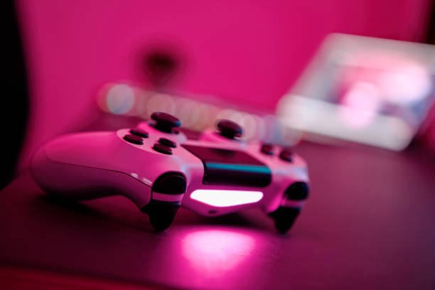 istock Close-up of gaming controller laying on table in purple illuminated room. Selective focus. 1336373812