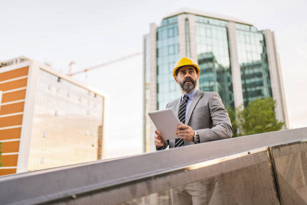 istock Mid adult architect using digital tablet and examining a digital blueprint at construction site. 1336376297