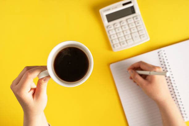 istock close up on hand holding pencil writing on notebook by the calculator on yellow background - office and business planning or goals coffee break concept 1336383949