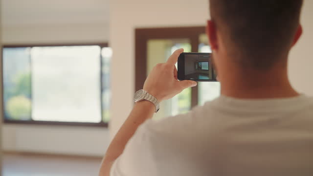 Young man using smart phone to film new house