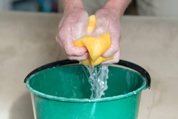 istock Male hands squeezing water from a cleaning sponge 1336388094