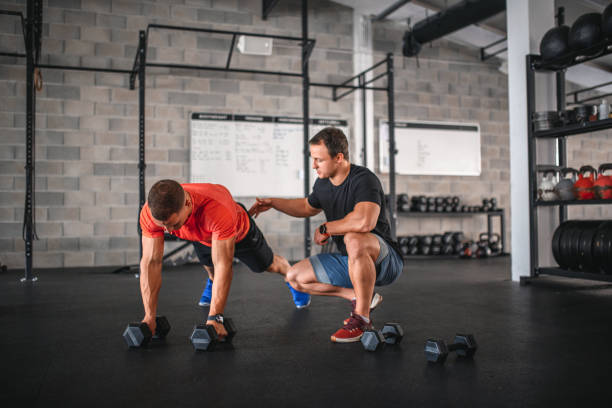 istock Coach Supervising Athlete as He Does Renegade Row Push-Ups 1336391365