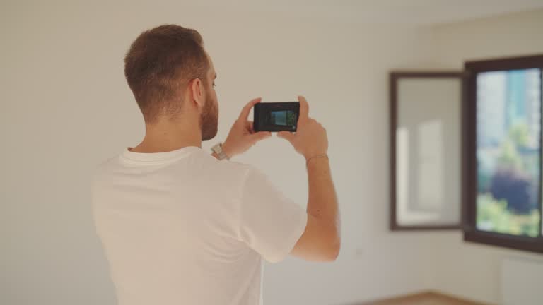 Young man using smart phone to film new house