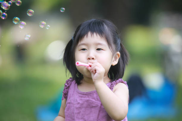 istock Girl playing with soap bubbles 1336399960