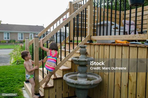 Two Kids Getting Around Pool Security Gate Stock Photo - Download Image Now - Staircase, Patio, Playful