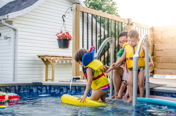 istock Father and mixed race children entering in pool water 1336404004