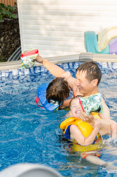 istock Mixed race children playing in pool with father 1336404181