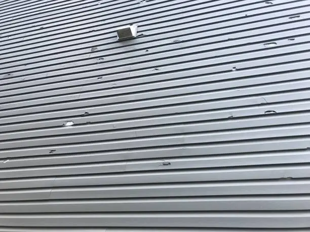 The broken vinyl siding on a house due to hail