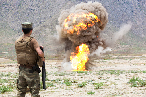 Army Soldier standing against explosion in battlefield