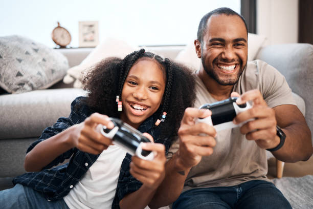 scatto di una ragazza che gioca ai videogiochi con suo padre a casa - video game family child playful foto e immagini stock