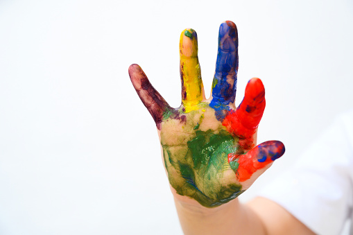 Colourful painted child hand up isolated on white background. Creative, funny, artistic and happy