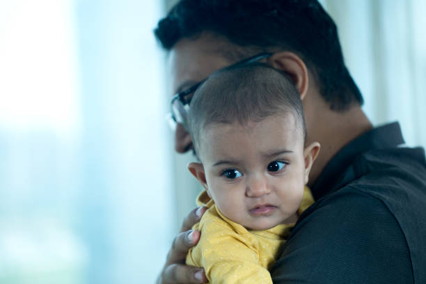 Loving father carrying adorable baby son at home