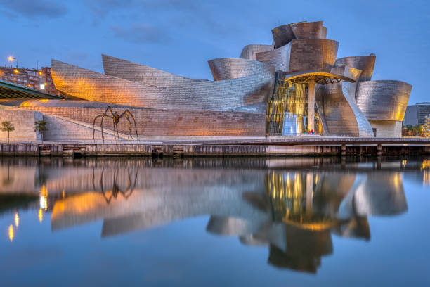 The famous Guggenheim Museum reflected in the River Nervion at dawn Bilbao, Spain - July 10, 2021: The famous Guggenheim Museum reflected in the River Nervion at dawn estuary stock pictures, royalty-free photos & images