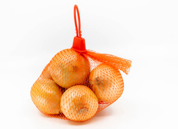 isolated fresh organic onions in a red net bag on white background - onion bag netting vegetable imagens e fotografias de stock