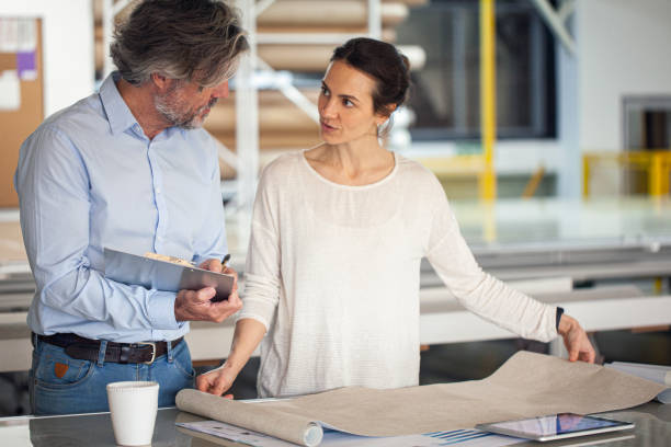 istock Employer and employee discussing project ideas while standing inside production factory 1336419079