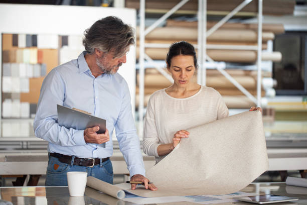 Sustainable designer sharing ideas with colleague inside textile factory stock photo
