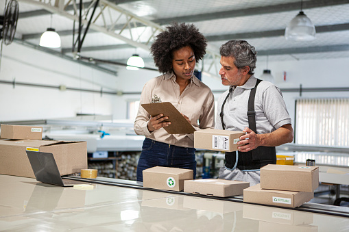 Male and female warehouse colleagues preparing packages for delivery at workplace