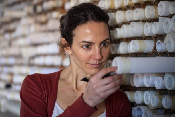istock Portrait of textile designer choosing fabric from stack of rolls inside sustainable workshop 1336419328