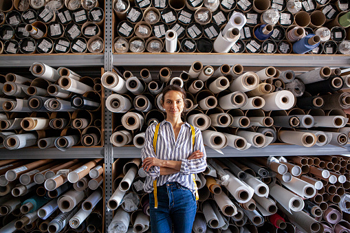 Portrait of young textile designer standing inside textile workshop during daytime