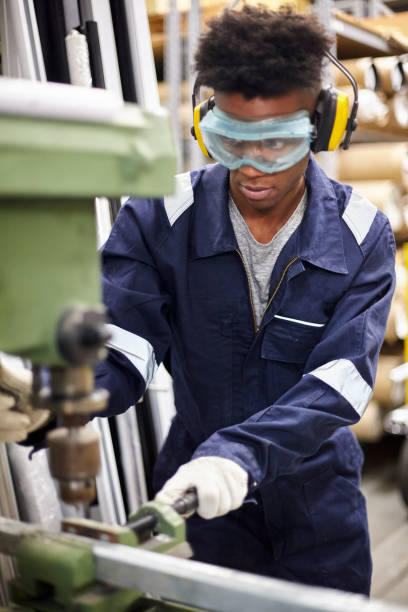 istock Portrait of young factory operator wearing protective earmuffs and plastic eyeglasses while using industrial machinery 1336419462