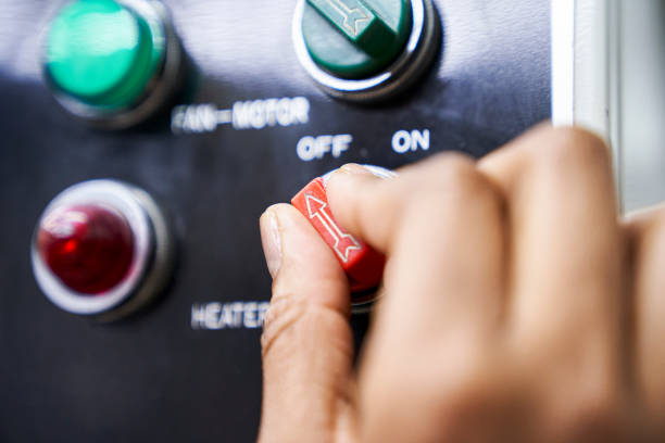 Female hand using switch panel of industrial machinery inside factory