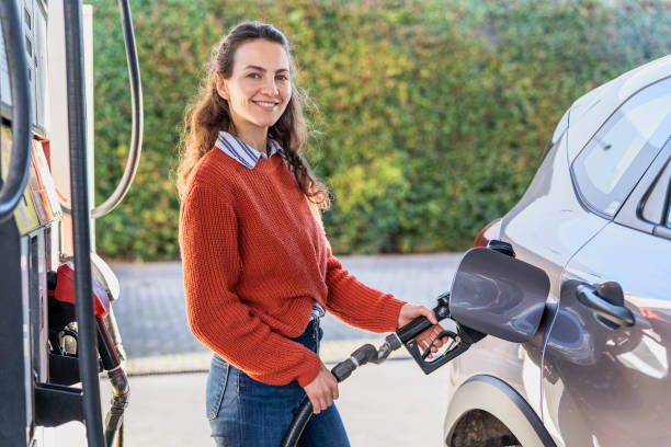portrait of young adult woman filling fuel tank while standing next to car - 1750 imagens e fotografias de stock
