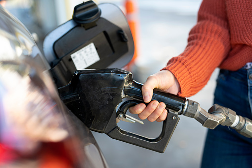 Close up of female hand loading fuel to car while standing in filling station