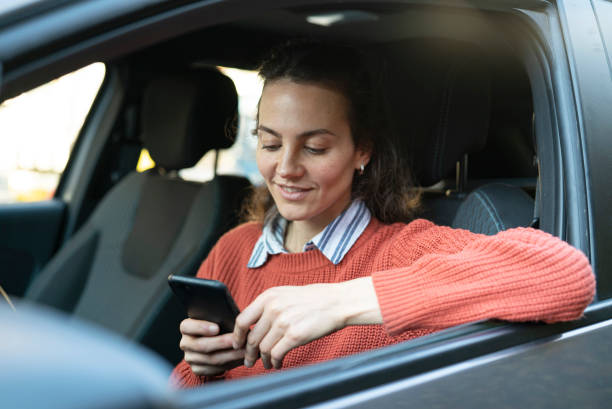 Portrait of smiling male mature adult using mobile phone while sitting on driver´s seat of a car stock photo