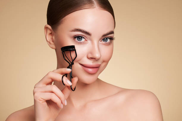 Beautiful woman using eyelash curler stock photo