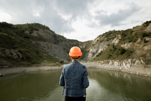 Female engineer watching on the lake in the quarry. View from behind